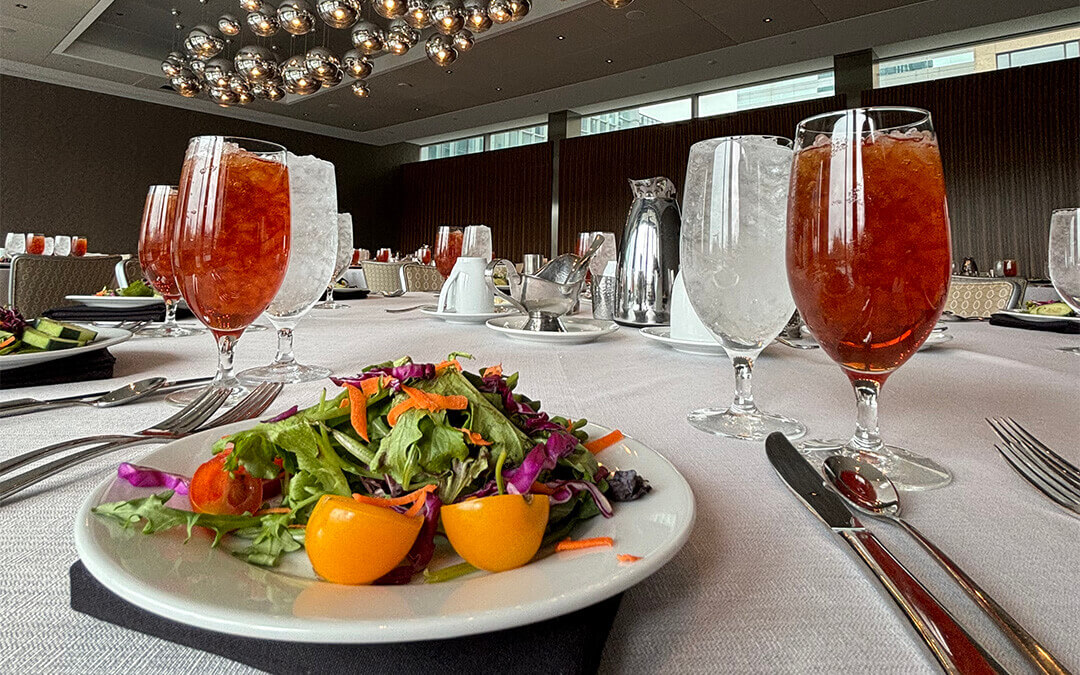 A plate of salad and glasses of water and tea at the OKC CDA Luncheon.